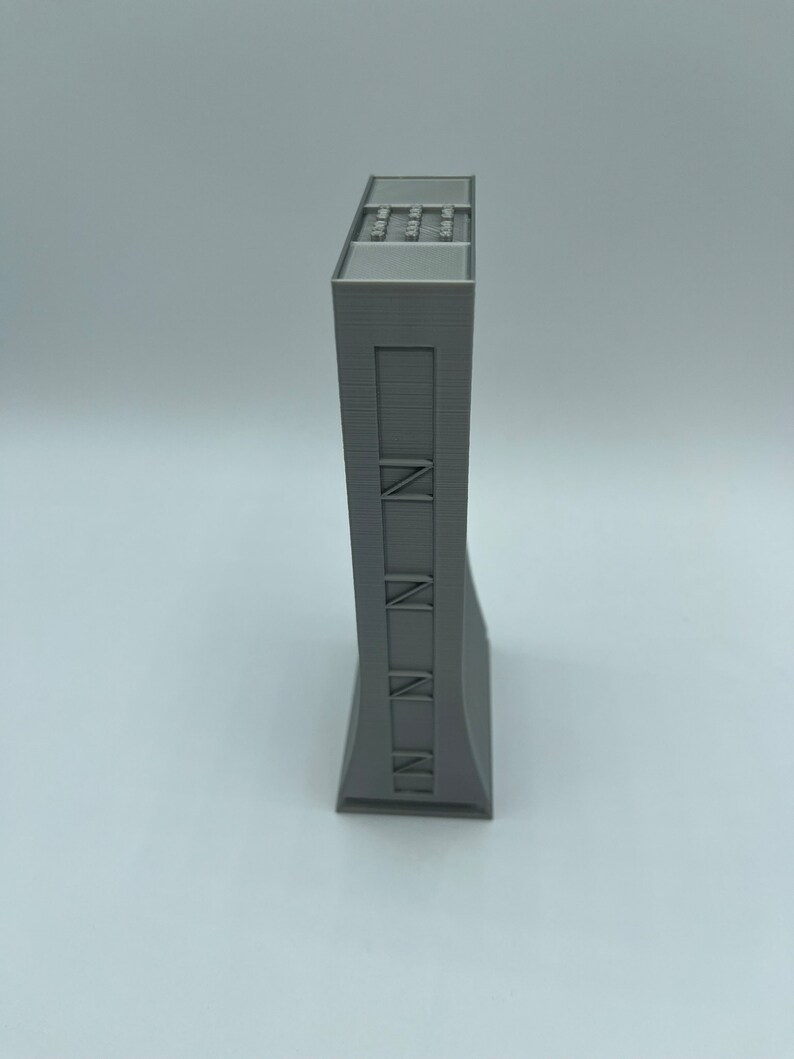 May include: A gray 3D printed model of a tall building with a flat roof and a series of windows on the front.