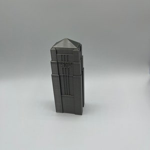 Peut inclure: Mod&egrave;le miniature d'un gratte-ciel avec une finition m&eacute;tallique grise. Le b&acirc;timent a un toit plat et une forme rectangulaire. Le b&acirc;timent a une petite enseigne qui indique "WAYNE" sur le devant.