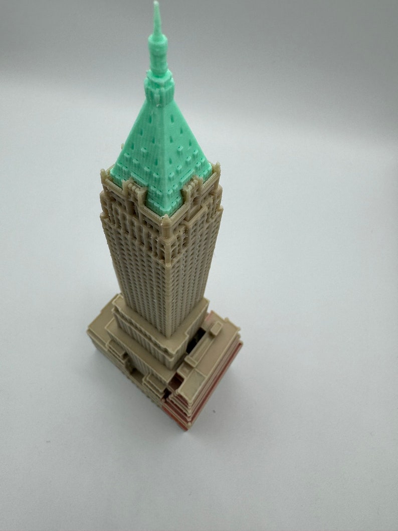 May include: A 3D printed model of a skyscraper with a green roof and brown walls. The model is detailed with windows and a base.