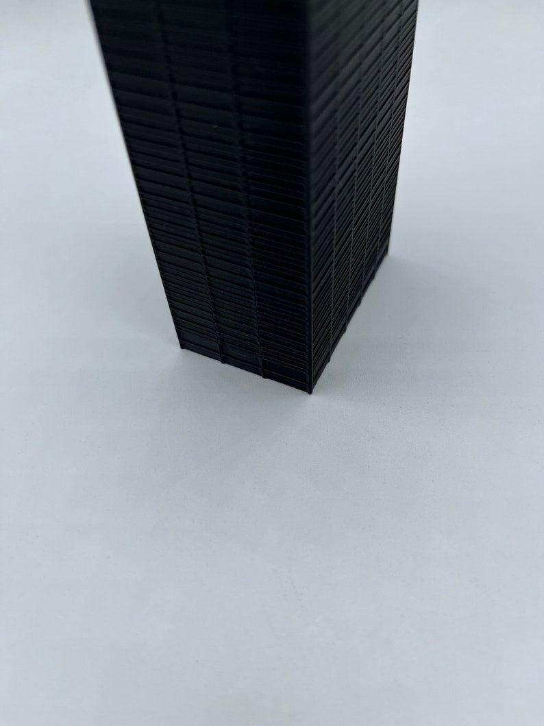 May include: A black, rectangular, 3D printed model of a skyscraper.