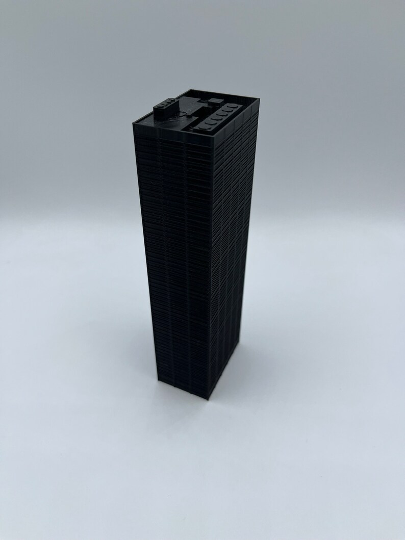 May include: A black miniature model of a skyscraper with a flat roof and many windows.