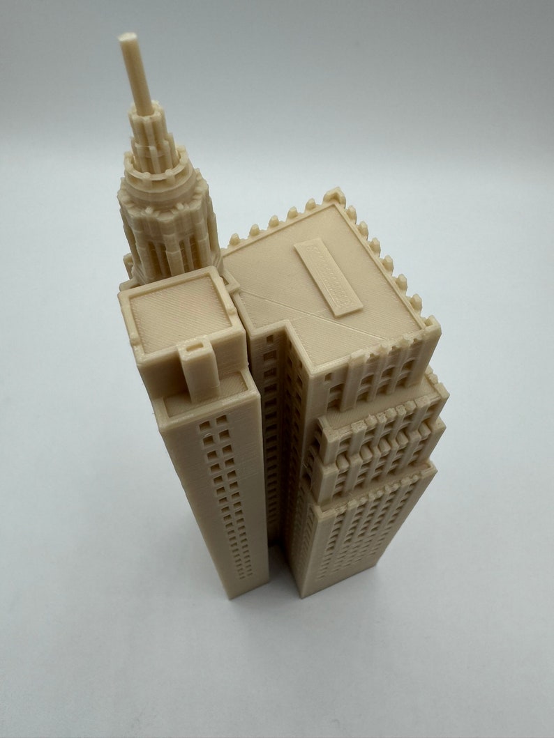 Pu&ograve; includere: Un modello di grattacielo stampato in 3D di colore beige con un tetto a punta e una facciata dettagliata.