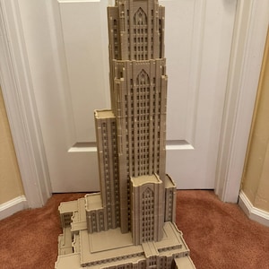 Puede incluir: Un modelo impreso en 3D detallado de un edificio alto de color beige con estilo arquitect&oacute;nico g&oacute;tico. El modelo presenta detalles intrincados, incluyendo ventanas, arcos y un techo puntiagudo.