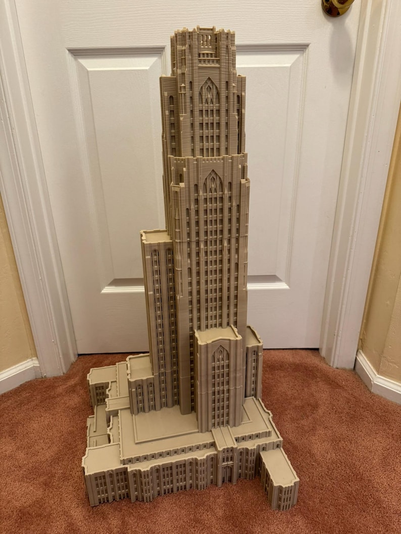 Puede incluir: Un modelo impreso en 3D detallado de un edificio alto de color beige con estilo arquitect&oacute;nico g&oacute;tico. El modelo presenta detalles intrincados, incluyendo ventanas, arcos y un techo puntiagudo.