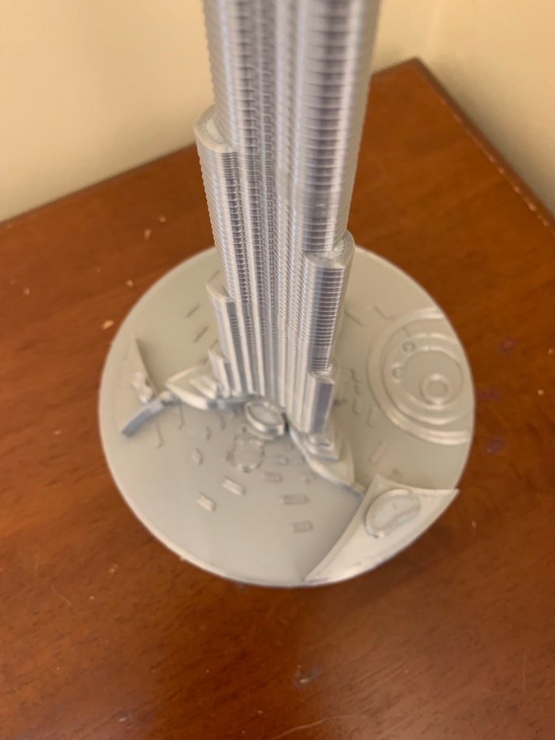 May include: A silver model of the Burj Khalifa, a skyscraper in Dubai, with a detailed base.