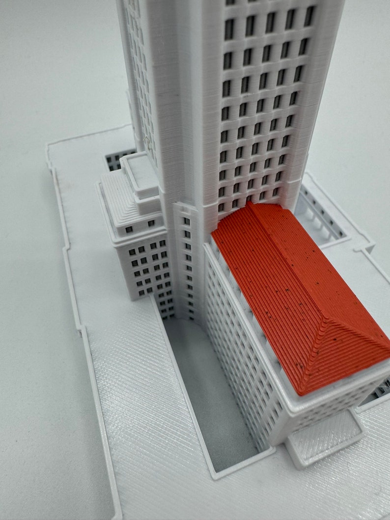 May include: A white 3D printed model of a building with a red roof. The building has many windows and a detailed facade.