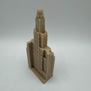 May include: A beige 3D printed model of a tall building with a clock tower and a domed roof.