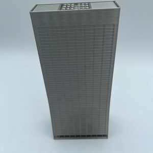 May include: A gray, rectangular model of a skyscraper with a flat roof and a grid pattern on the facade.