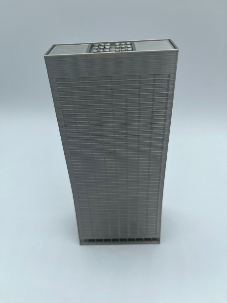 May include: A gray, rectangular model of a skyscraper with a flat roof and a grid pattern on the facade.