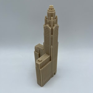 May include: A beige 3D printed model of a tall skyscraper with a domed roof and intricate details.