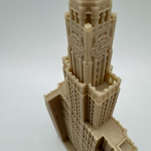 May include: A detailed 3D printed model of a tall, beige building with a clock tower and intricate architectural details.