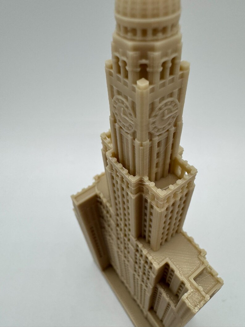May include: A detailed 3D printed model of a tall, beige building with a clock tower and intricate architectural details.