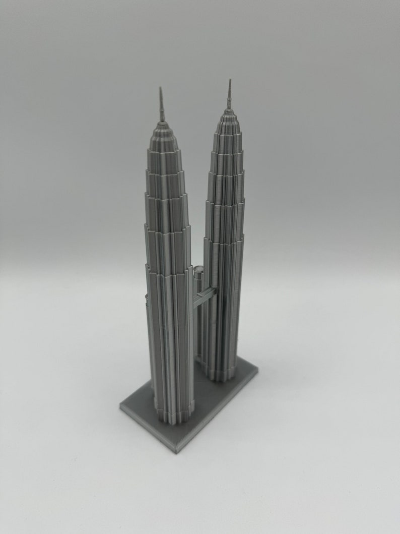May include: A gray 3D printed model of the Petronas Towers, a famous landmark in Kuala Lumpur, Malaysia.