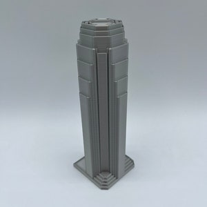 May include: A gray 3D printed model of a skyscraper with a detailed facade.