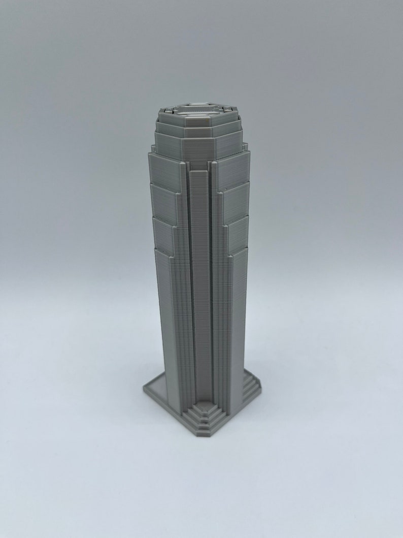 May include: A gray 3D printed model of a skyscraper with a detailed facade.