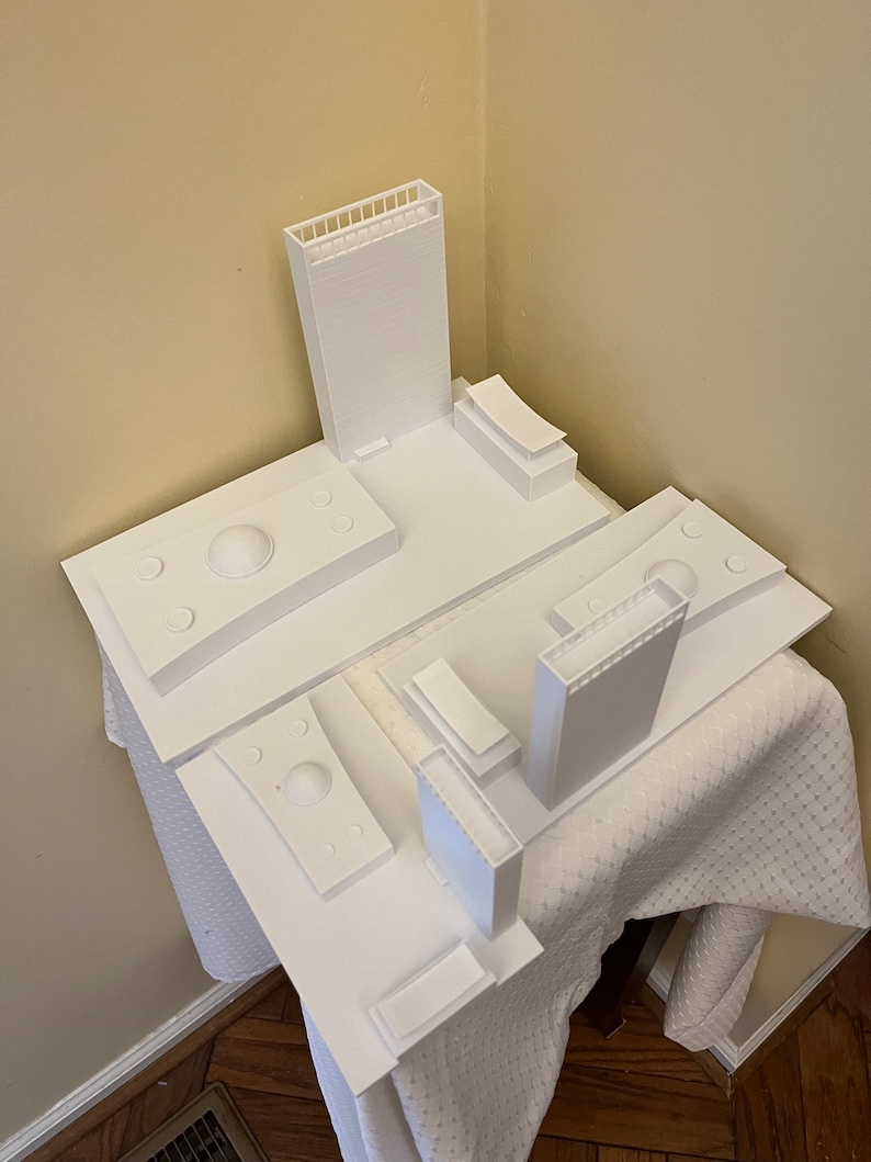 K&ouml;nnte beinhalten: Ein wei&szlig;es 3D-gedrucktes Modell einer Skyline mit mehreren Geb&auml;uden und einer Kuppelstruktur. Das Modell steht auf einer wei&szlig;en Oberfl&auml;che.