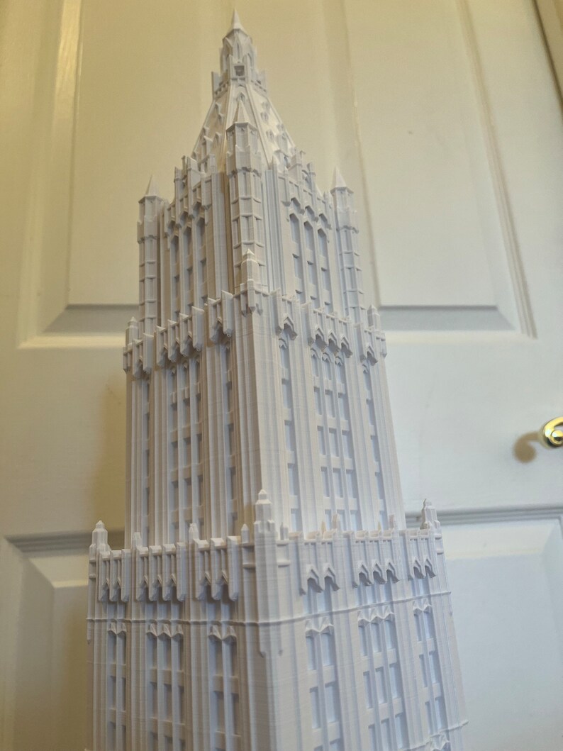 May include: A white 3D printed model of a tall, ornate building with a pointed roof and many windows.