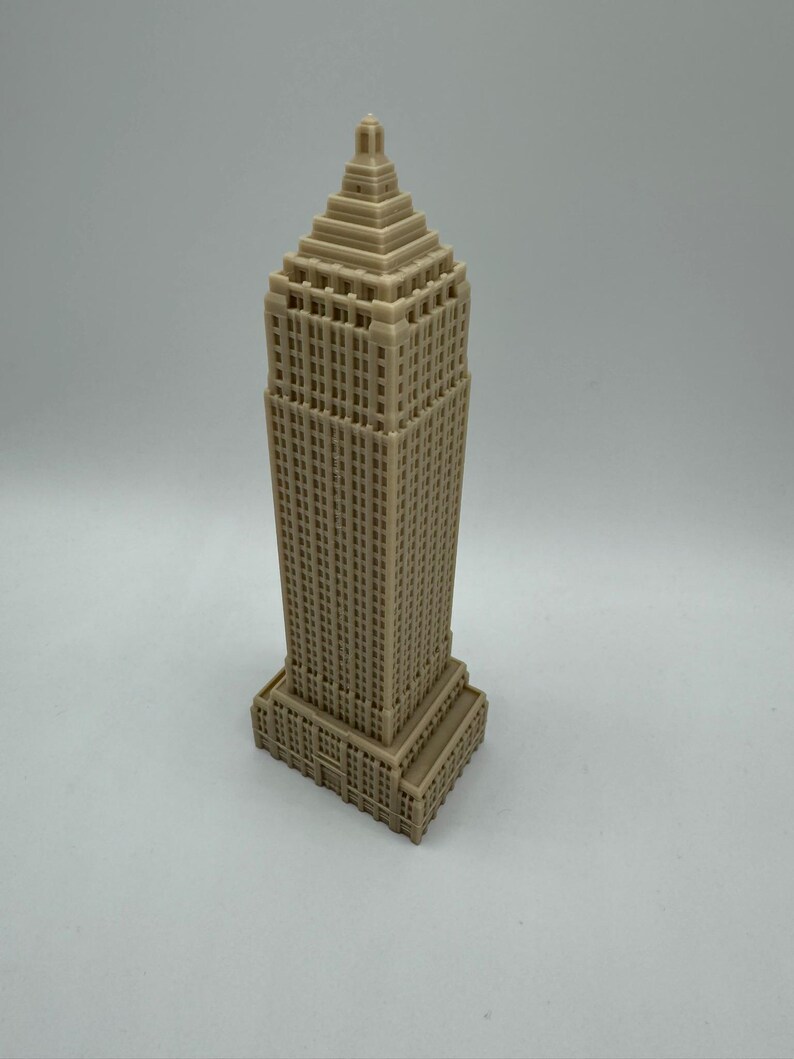 Puede incluir: Un modelo de rascacielos impreso en 3D de color beige con un techo puntiagudo y muchas ventanas.