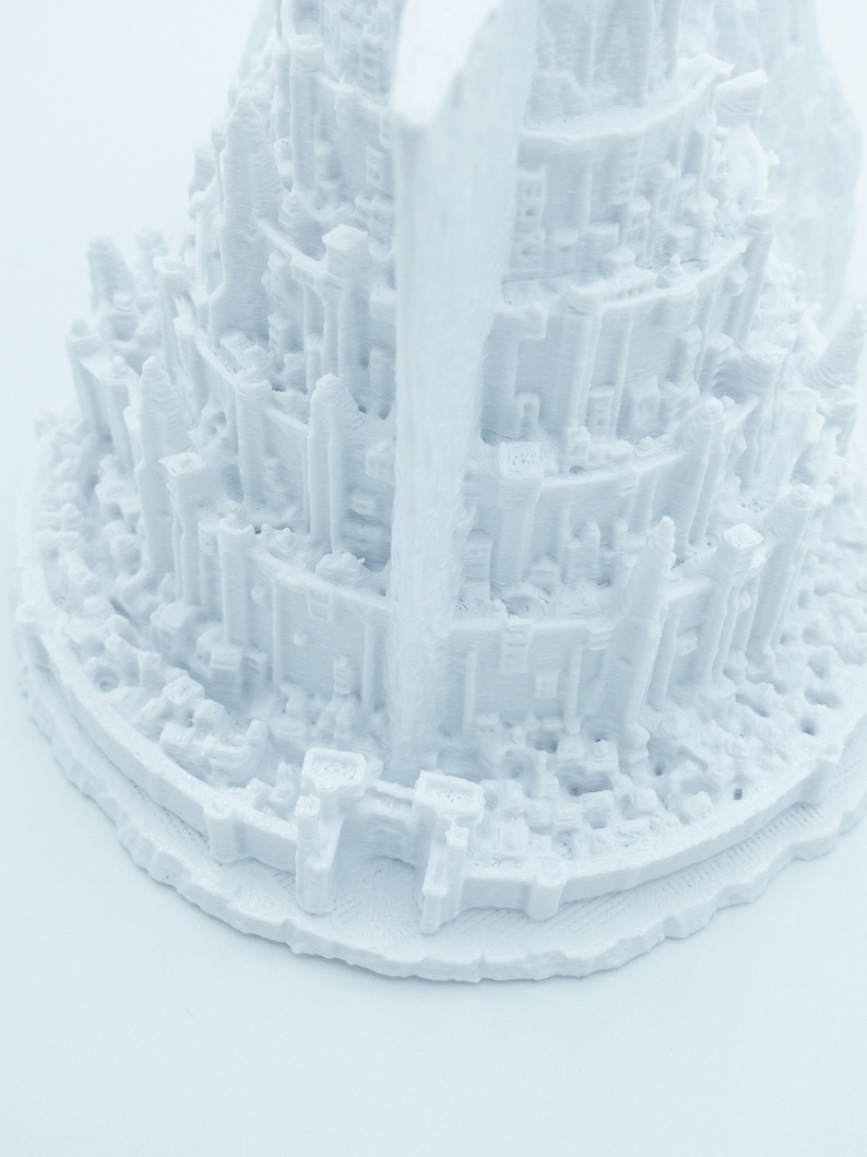 May include: White 3D printed model of a tall, multi-level structure with intricate details. The model is made of a smooth, white plastic and has a circular base.