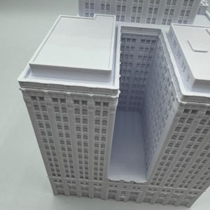 Puede incluir: Maqueta arquitect&oacute;nica blanca de una manzana de la ciudad, con varios rascacielos. El modelo tiene fachadas detalladas con numerosas ventanas y tejados planos. Los edificios est&aacute;n conectados, creando un dise&ntilde;o urbano &uacute;nico.