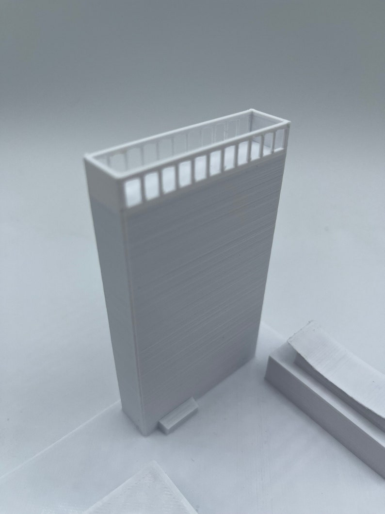 K&ouml;nnte beinhalten: Ein wei&szlig;es 3D-gedrucktes Modell eines Geb&auml;udes mit einem Balkon und einer kleinen Stufe, die zu ihm f&uuml;hrt.