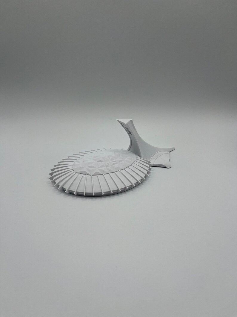 May include: A white 3D printed model of a modern building with a curved roof and a pointed spire.