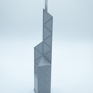May include: A gray, 3D-printed model of a skyscraper with a distinctive geometric design. The building features a series of triangular and rectangular shapes, with two tall spires at the top. The model is set against a plain white background.