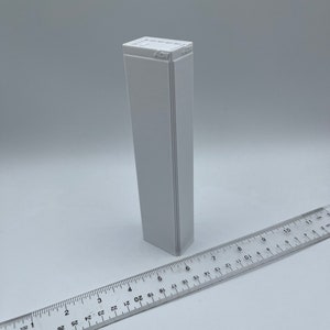 K&ouml;nnte beinhalten: Eine wei&szlig;e rechteckige Box mit dem Text "457" auf der Oberseite. Die Box ist etwa 15 cm hoch und 2,5 cm breit.