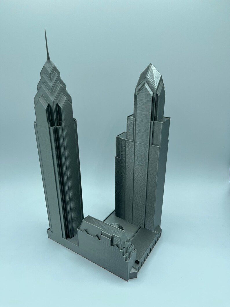 May include: A 3D printed model of two skyscrapers, one taller than the other, with a gray metallic finish.