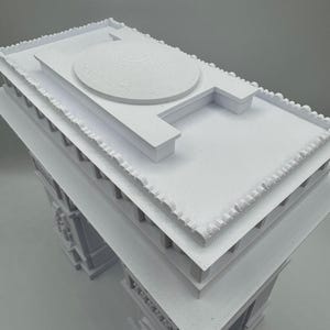 Może przedstawiać: Biały model architektoniczny budynku z kopulastym dachem i szczeg&oacute;łową fasadą. Model ma wiele warstw i skomplikowane wzory, prezentujące klasyczny styl. Konstrukcja wykonana jest z litego, nieprzezroczystego materiału.