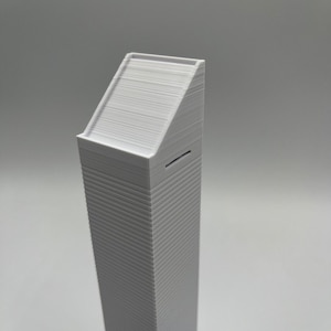 May include: A white 3D printed model of a skyscraper with a flat roof.