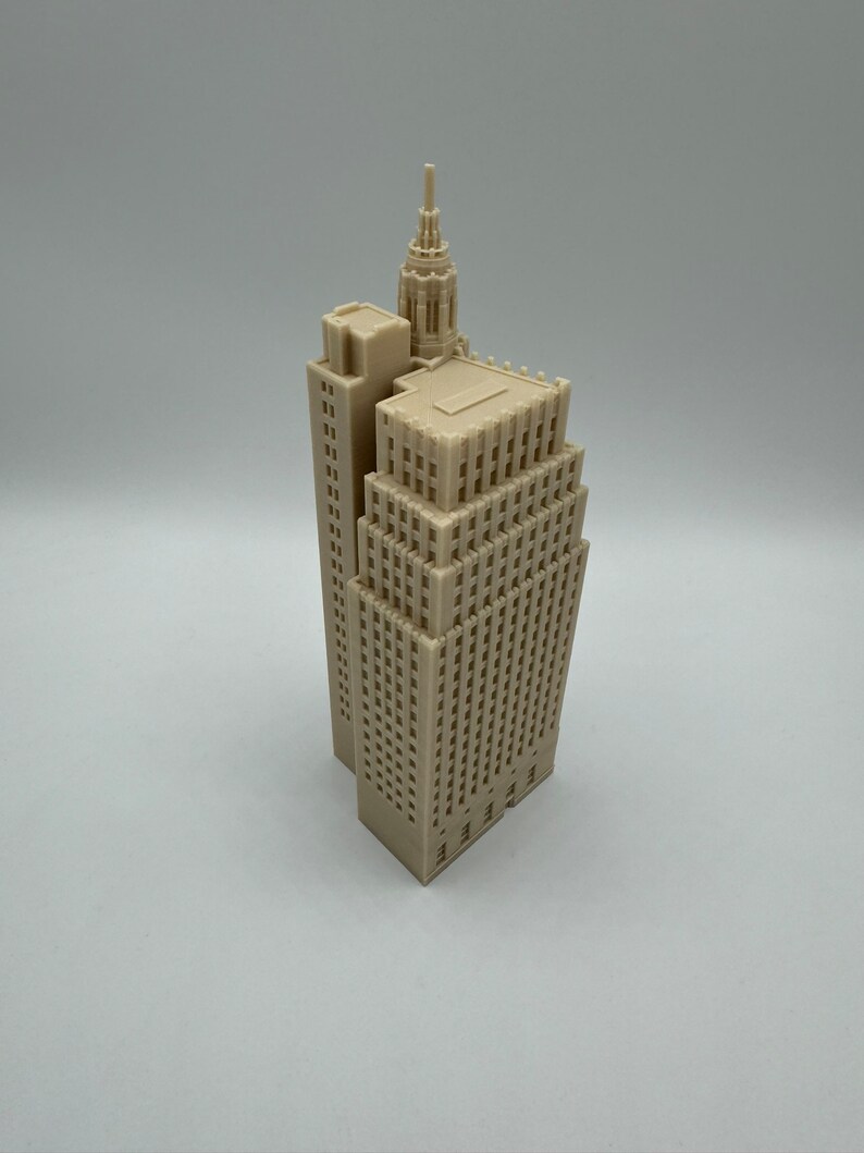 Pu&ograve; includere: Un modello di grattacielo stampato in 3D di colore beige con un tetto a punta e un edificio pi&ugrave; piccolo attaccato al lato.