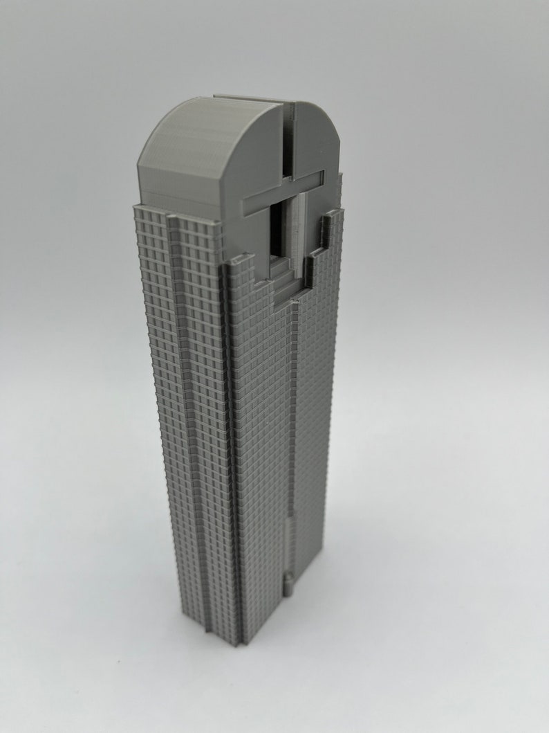 May include: A grey 3D printed model of a skyscraper with a rounded top and a detailed facade.