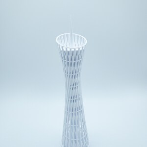 May include: A white 3D printed model of a tower with a pointed top and a lattice design.