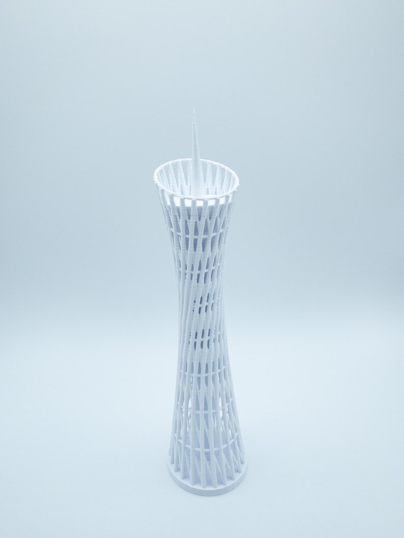 May include: A white 3D printed model of a tower with a pointed top and a lattice design.