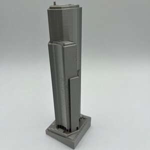 May include: A gray 3D printed model of a skyscraper.