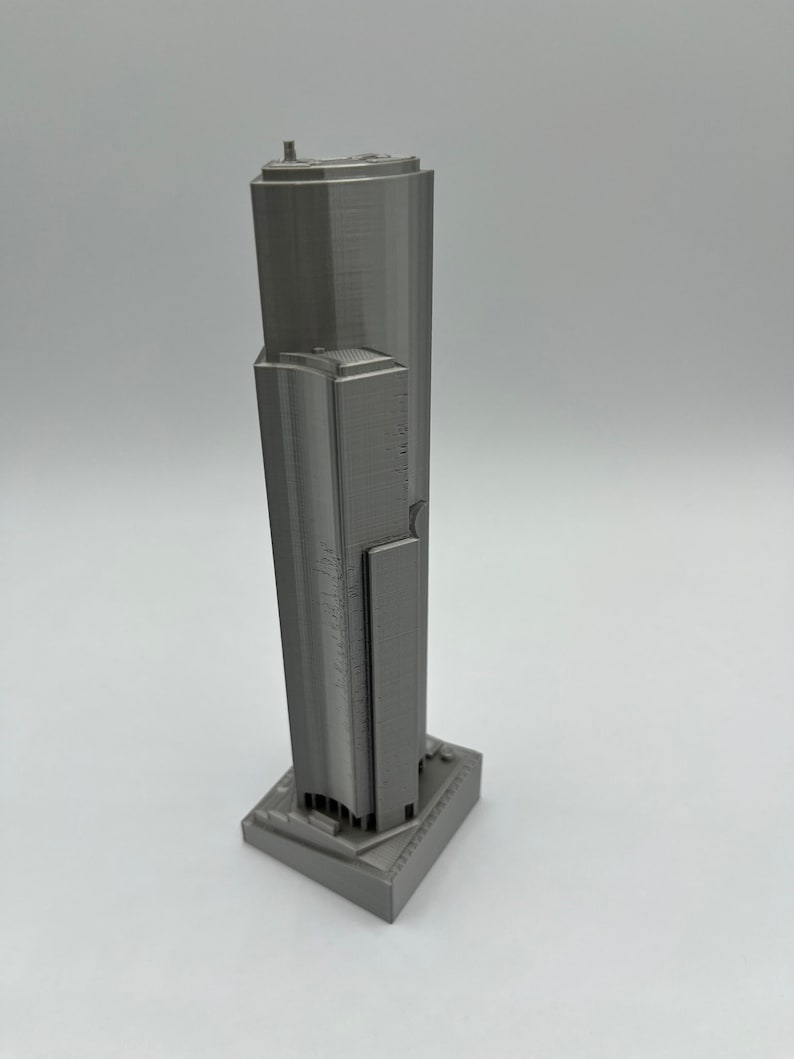 May include: A gray 3D printed model of a skyscraper.