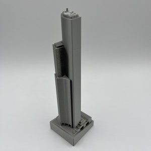 May include: A gray 3D printed model of a skyscraper.