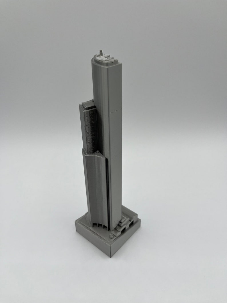 May include: A gray 3D printed model of a skyscraper.