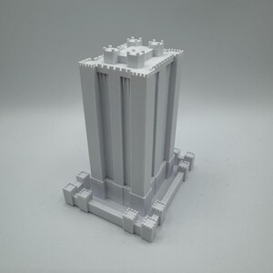 May include: A white 3D printed model of a tall, square tower with crenellations and a base. The tower has a simple design with no windows or doors.