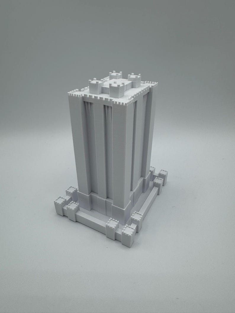 May include: A white 3D printed model of a tall, square tower with crenellations and a base. The tower has a simple design with no windows or doors.