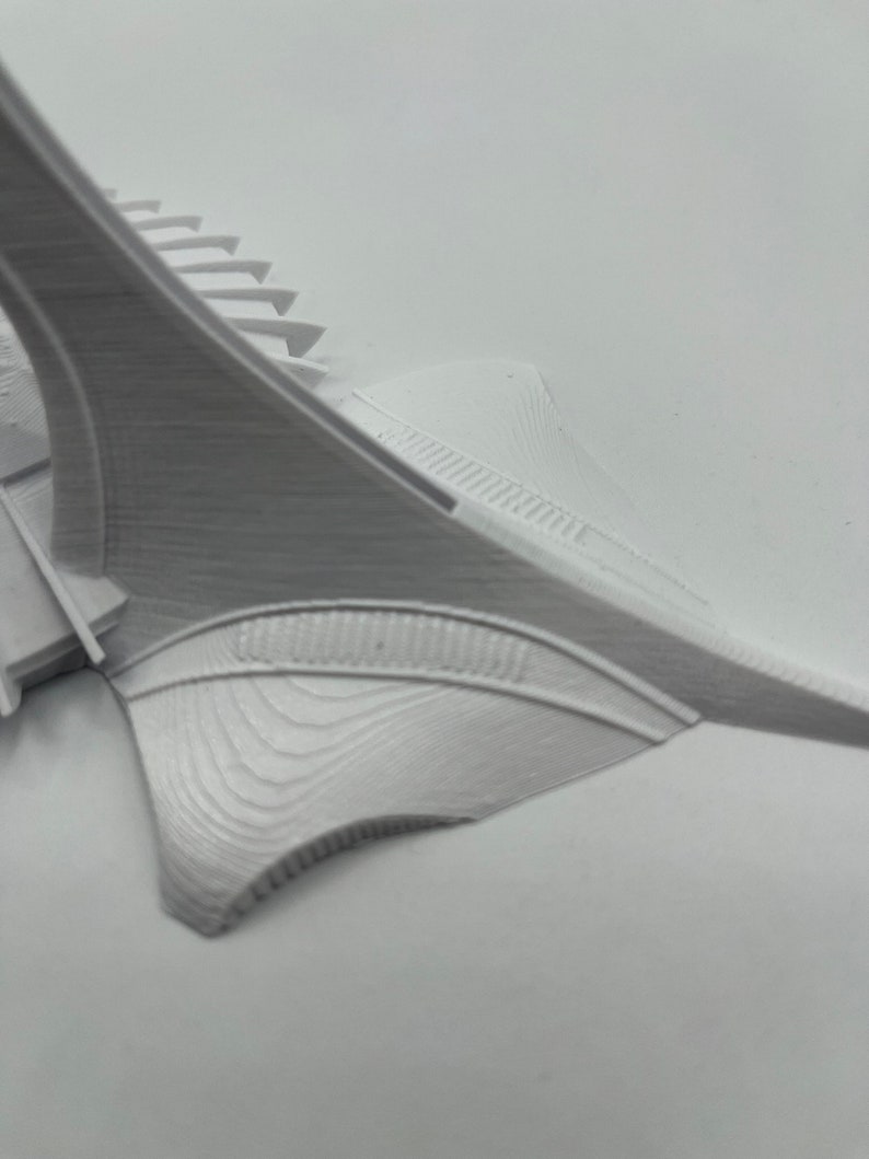May include: White 3D printed model of a building with a curved, pointed roof and a series of steps leading up to the roof.