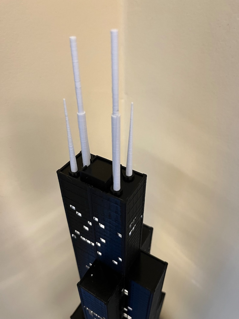 May include: A black and white model of a skyscraper with four white spires on top.