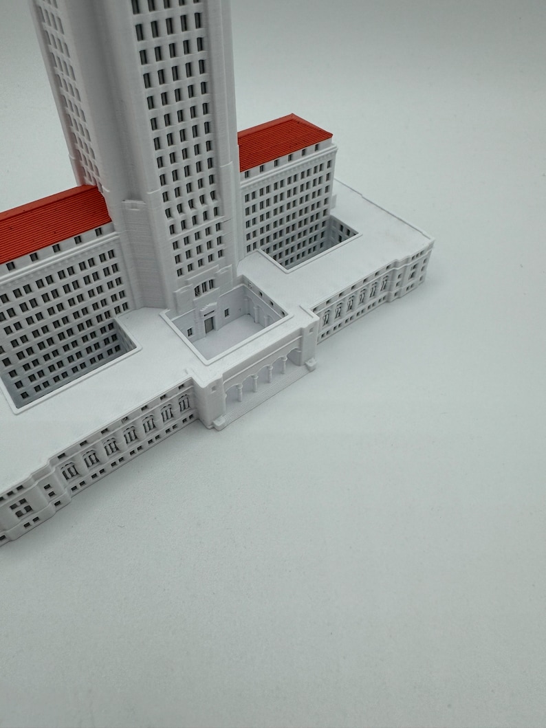 May include: A white 3D printed model of a building with a red roof. The building has a tall tower and two smaller wings.