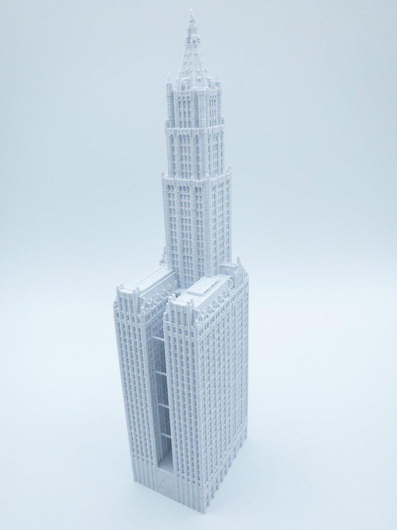 K&ouml;nnte beinhalten: Ein wei&szlig;es 3D-gedrucktes Modell eines hohen Wolkenkratzers mit einem spitzen Dach und vielen Fenstern.