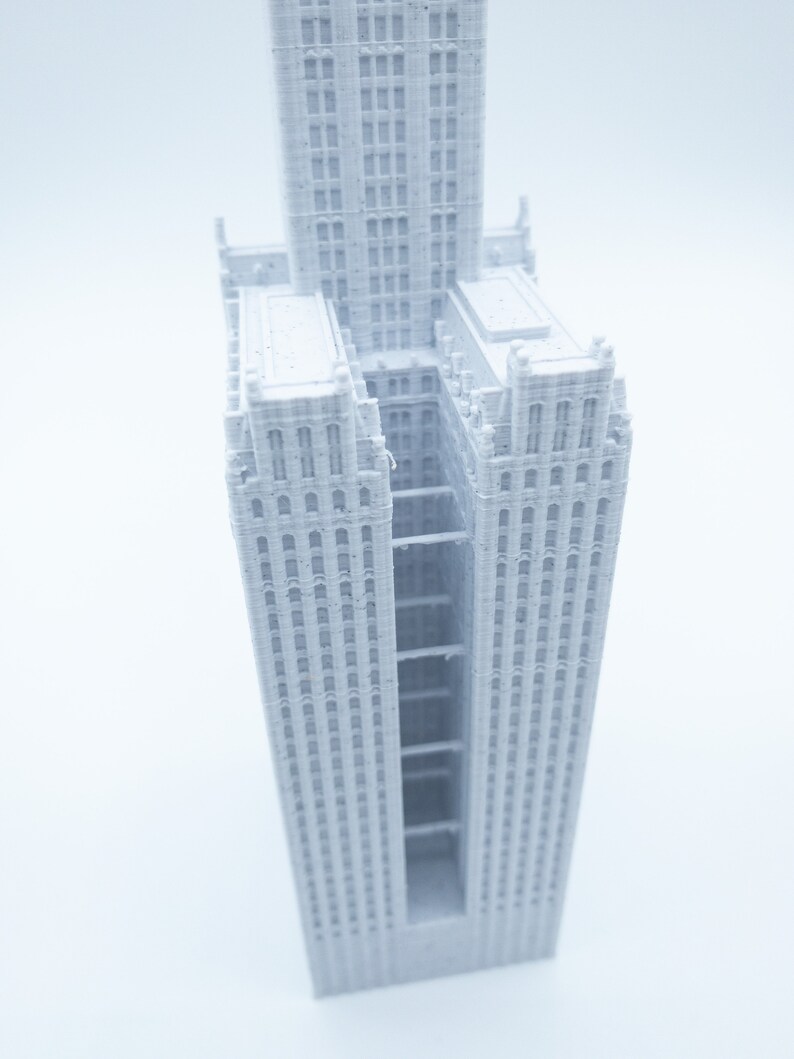 K&ouml;nnte beinhalten: Ein wei&szlig;es 3D-gedrucktes Modell eines hohen Geb&auml;udes mit einem zentralen, offenen Raum. Das Geb&auml;ude hat viele Fenster und eine detaillierte Fassade.