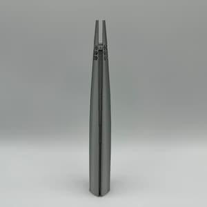 May include: A 3D printed model of a tall, slender building with a pointed top. The building is made of a gray material and has a textured surface.