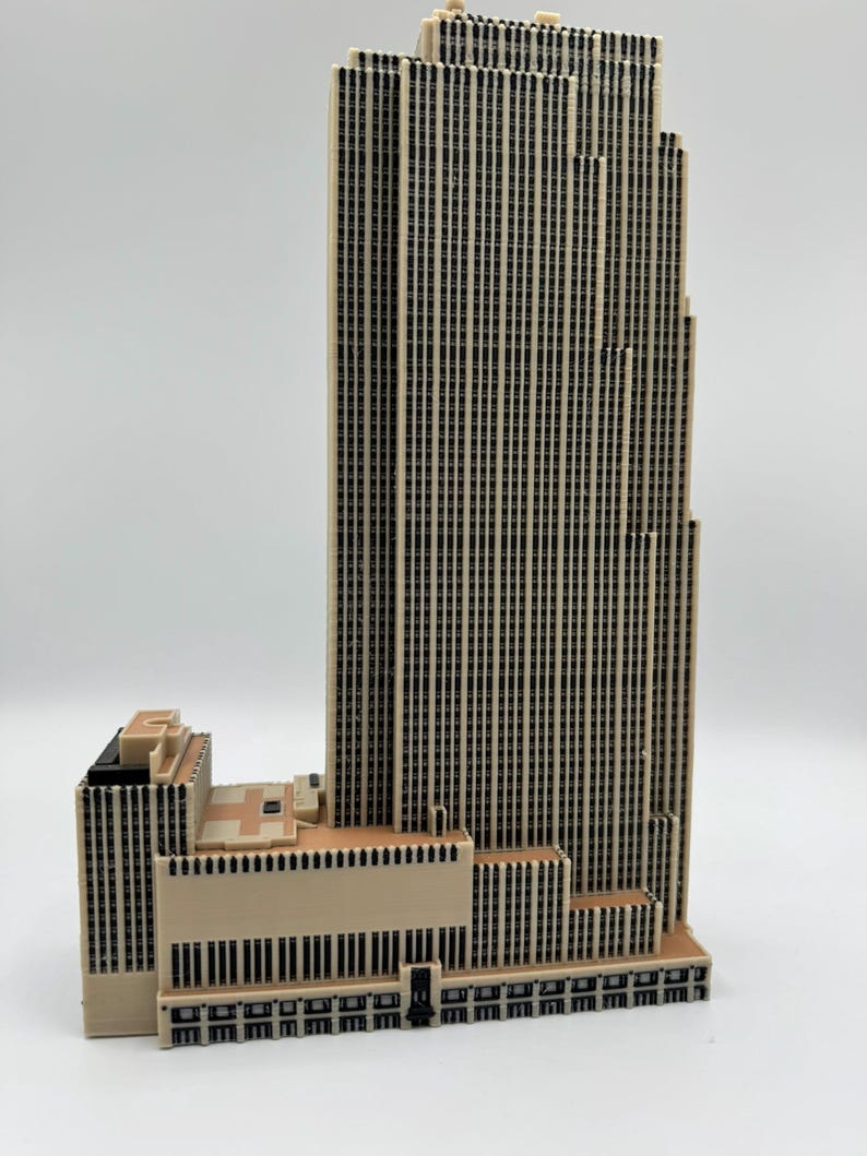 Puede incluir: Maqueta detallada de un rascacielos, con una fachada beige y numerosas ventanas negras. El edificio tiene un dise&ntilde;o escalonado, con una estructura central m&aacute;s alta y secciones adyacentes m&aacute;s bajas. El modelo mide aproximadamente 30 cm de altura.