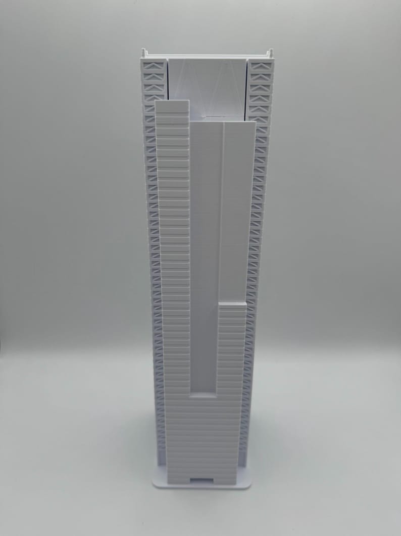 May include: A white, vertical, rectangular object with a textured surface. The object has a series of parallel lines and geometric shapes. The base is a solid white rectangle. The overall design is modern and minimalist.