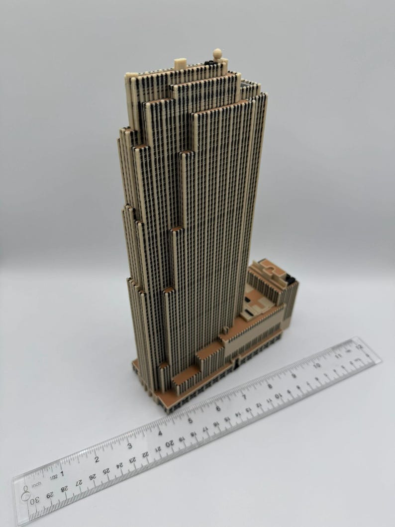 Puede incluir: Modelo detallado de un rascacielos en beige y marr&oacute;n. El edificio presenta un dise&ntilde;o distintivo con l&iacute;neas verticales y una parte superior escalonada. Una regla se coloca junto al modelo para la escala, en cm.
